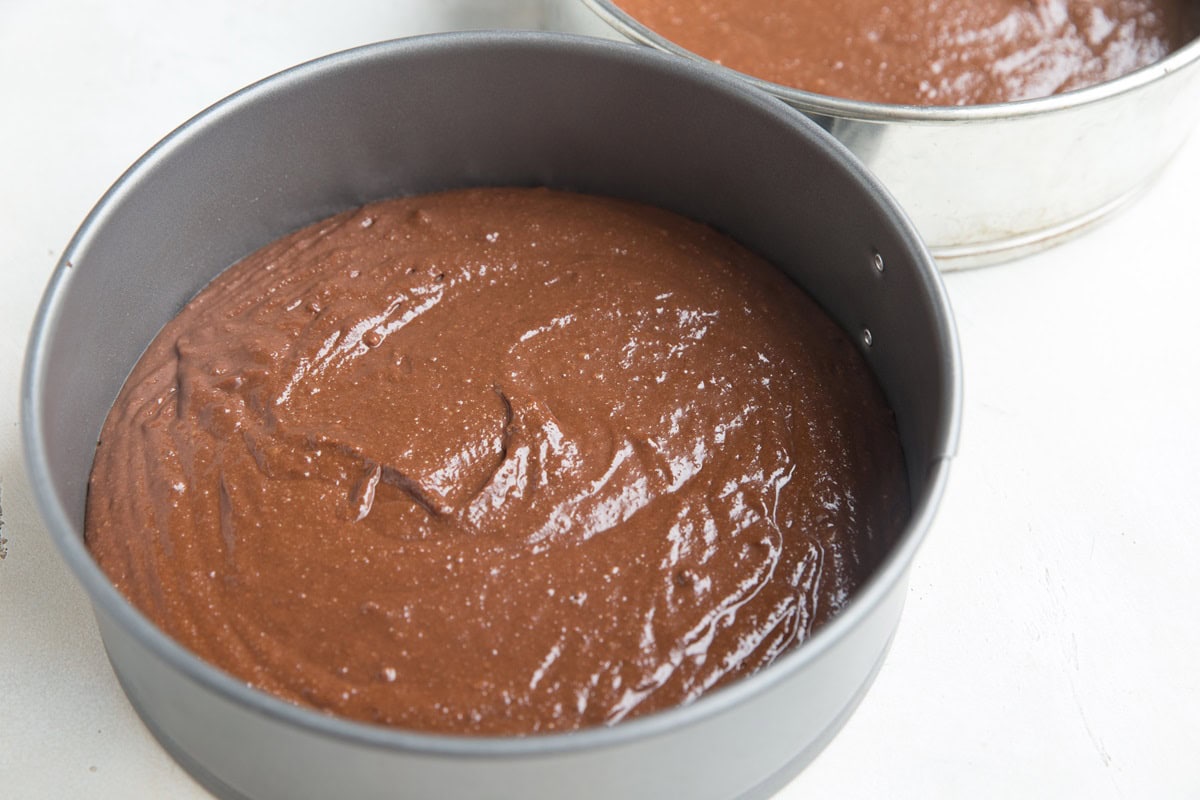 Two 8-inch cake pans with cake batter inside, ready to go into the oven.