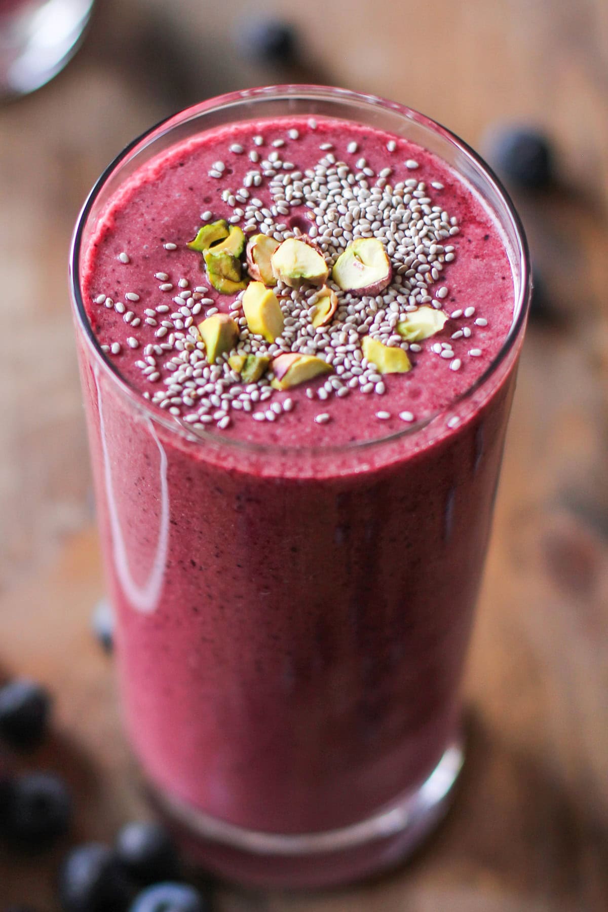 large glass of beet smoothie with chia seeds and chopped pistachios on top.