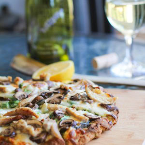 pizza with pesto sauce on a cutting board, sliced into slices.