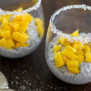 Two glasees of chia seed pudding with chopped mangos on top, ready to eat.