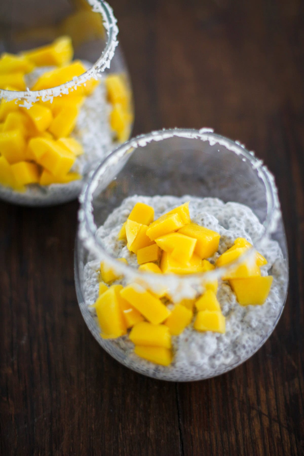 Two glasses with chia seed pudding and chopped mango inside. Ready to eat.