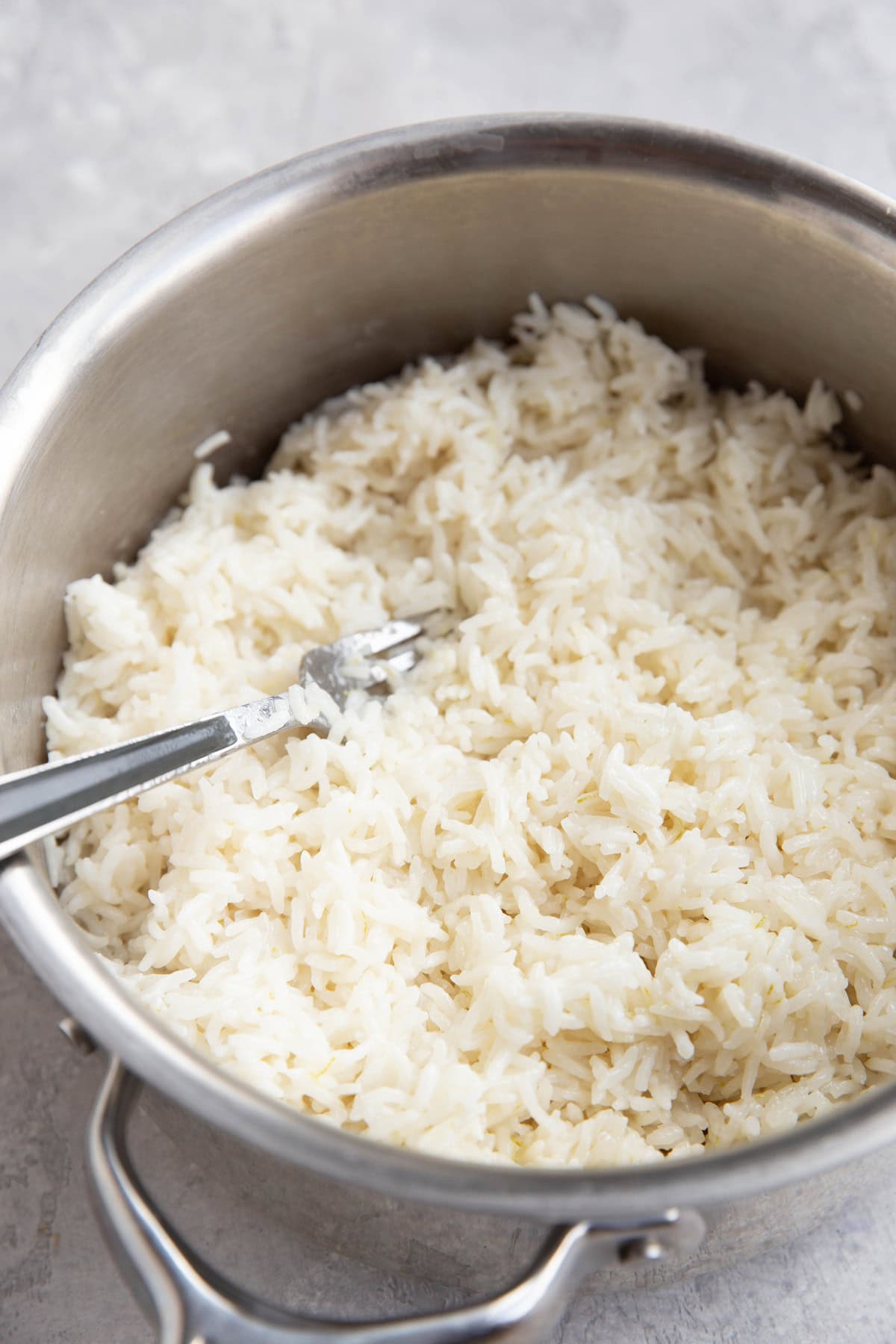 Saucepan of coconut rice with a fork fluffing the rice