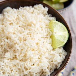 Big bowl of coconut rice with chopsticks to the side and a fresh lime.