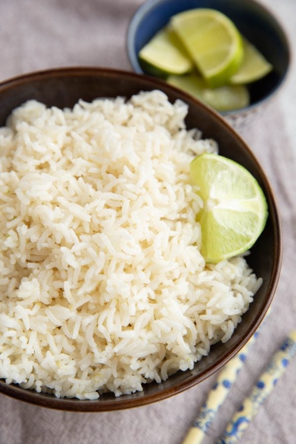 Big bowl of coconut rice with chopsticks to the side and a fresh lime.