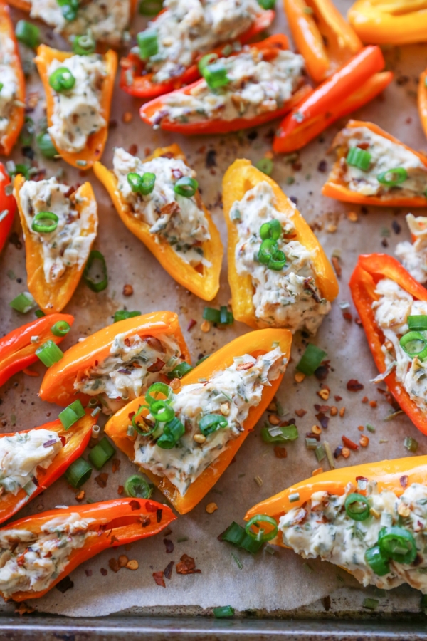 Rimmed baking sheet of mini sweet peppers stuffed with cream cheese.