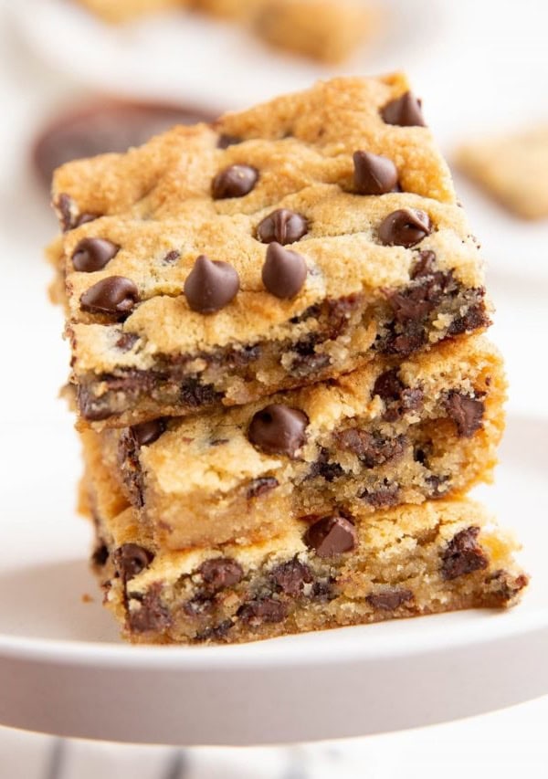 Three cookie bars stacked on top of each other on a white plate.