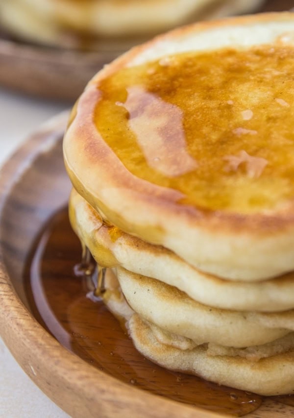 Close up shot of fluffy sourdough pancakes with syrup dripping down