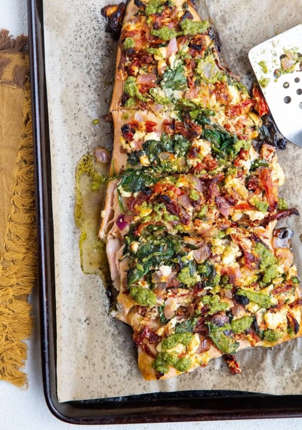 Full view of salmon on top of a baking dish with a spatula and a napkin to the side.