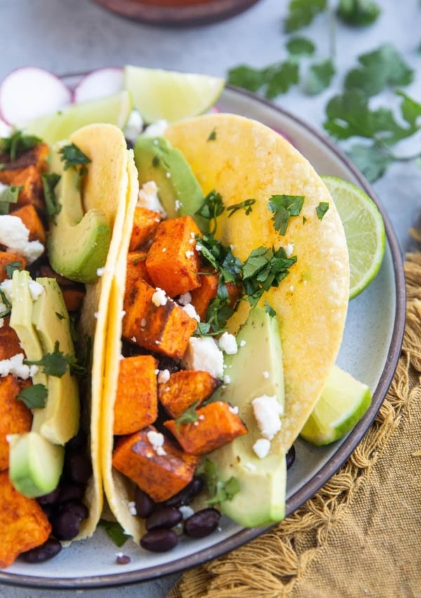 Vegetarian tacos with roasted vegetables and beans on a plate, ready to eat.