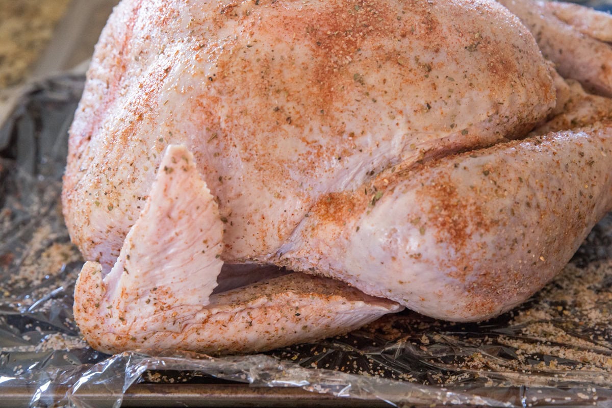 whole body turkey on a rimmed baking sheet covered with a dry rub.