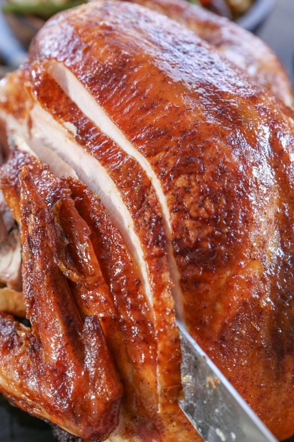 Whole Thanksgiving turkey being sliced into with a knife.