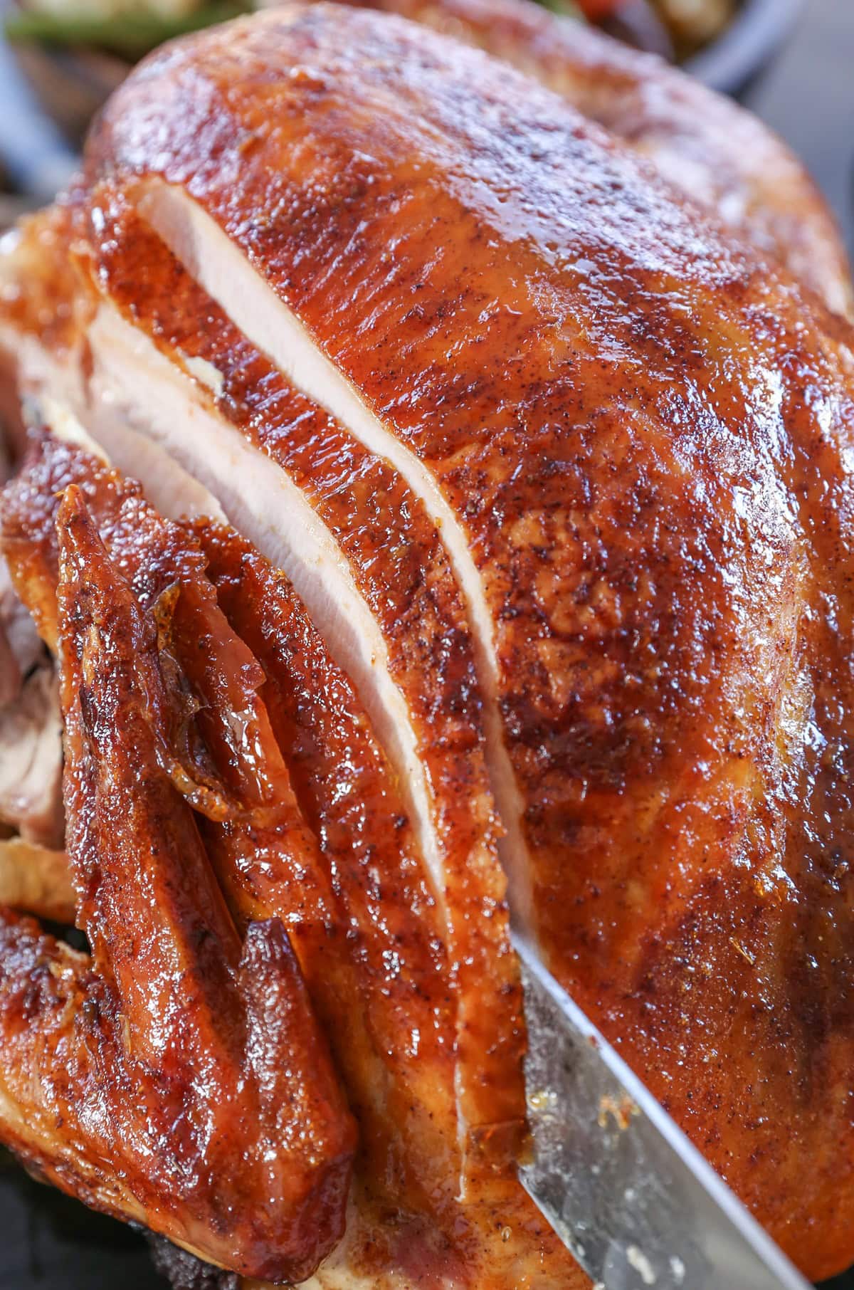 Whole Thanksgiving turkey being sliced into with a knife.