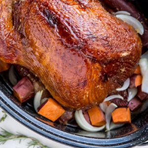 Dry brined turkey in a large roasting pan with sweet potatoes and onions at the bottom of the pan.