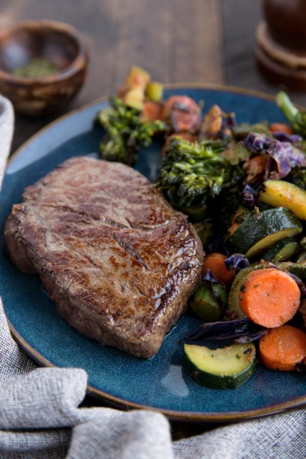 Steak on a plate with roasted vegetables, ready to serve.