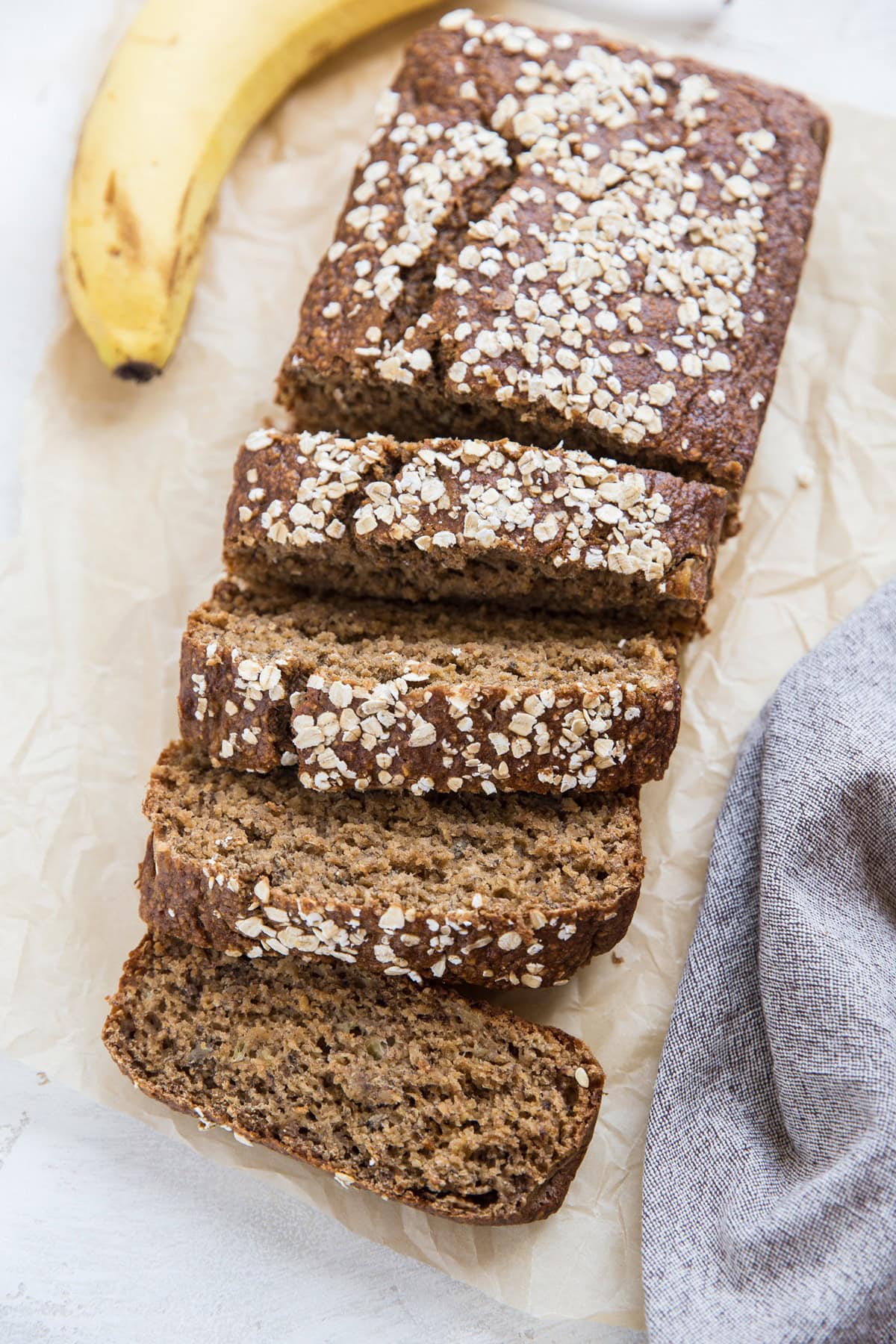 Oatmeal Banana Bread on parchment paper with a napkin and a banana