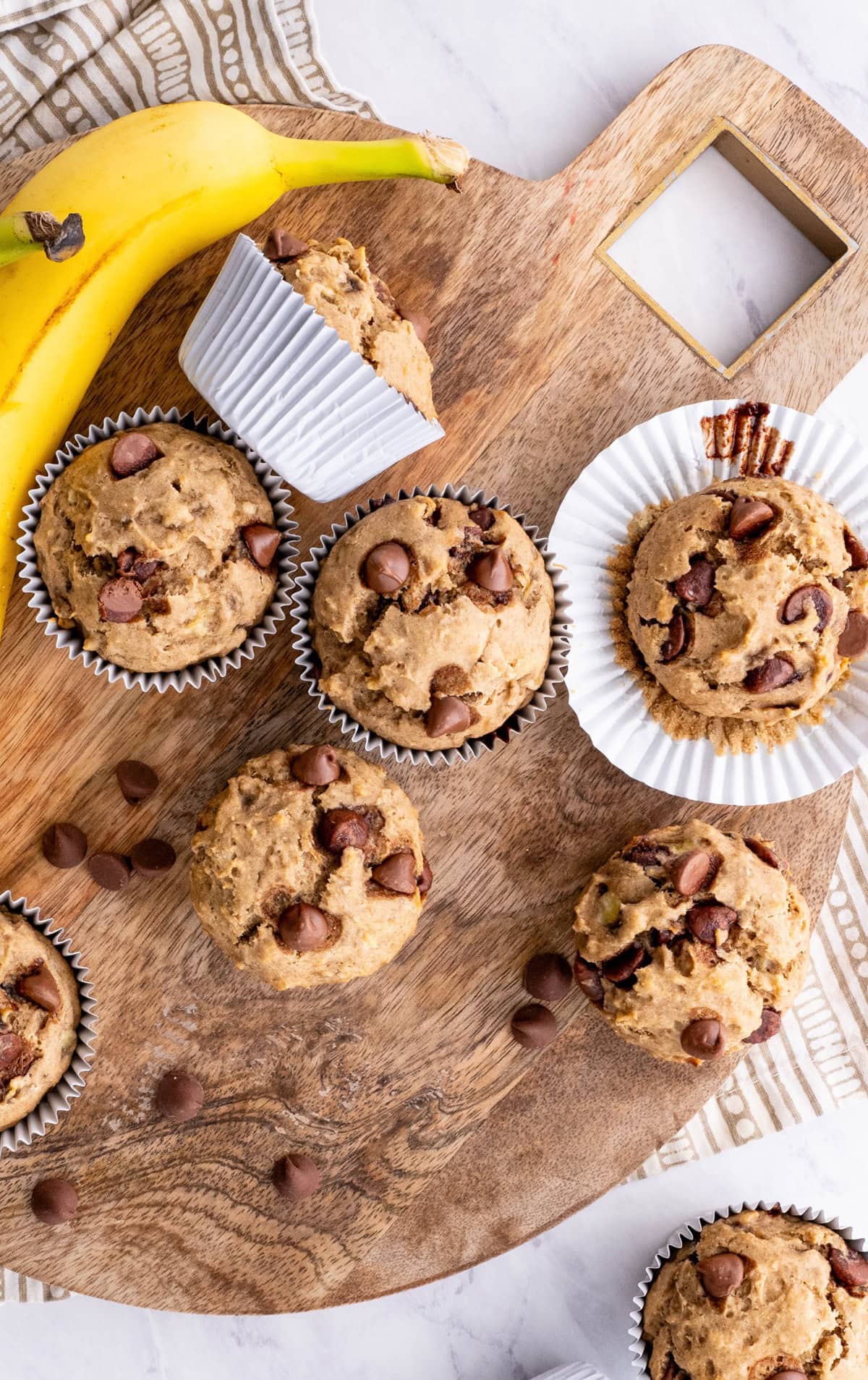 Moist and fluffy gluten-free banana muffins with chocolate chips - a delicious muffin recipe! Muffins are placed on a cutting board on a marble surface