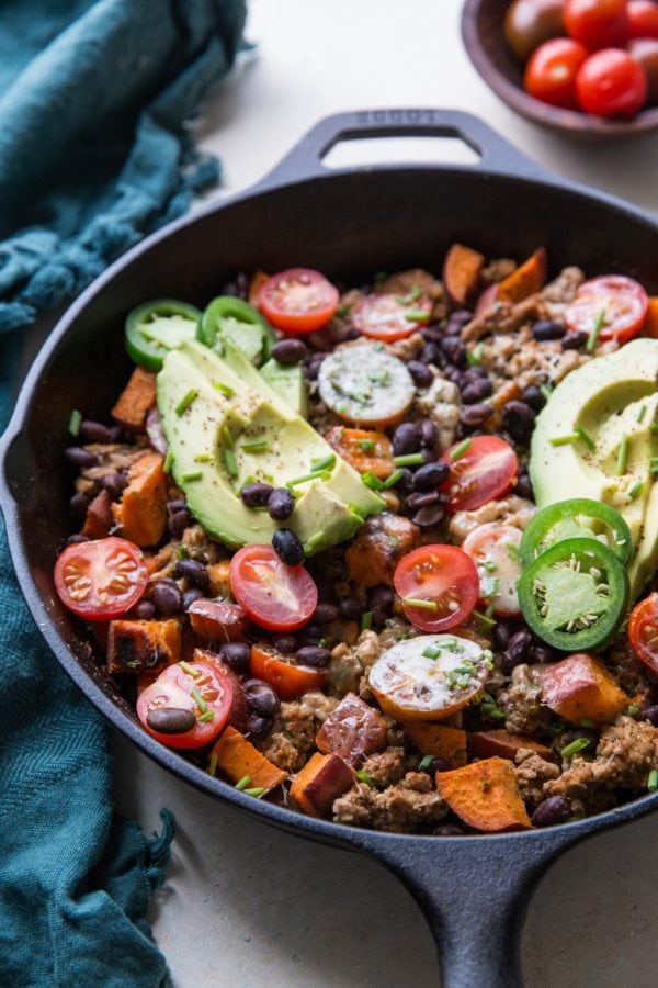 Cast iron skillet full of ground turkey, sweet potatoes, black beans, avocado, and more.