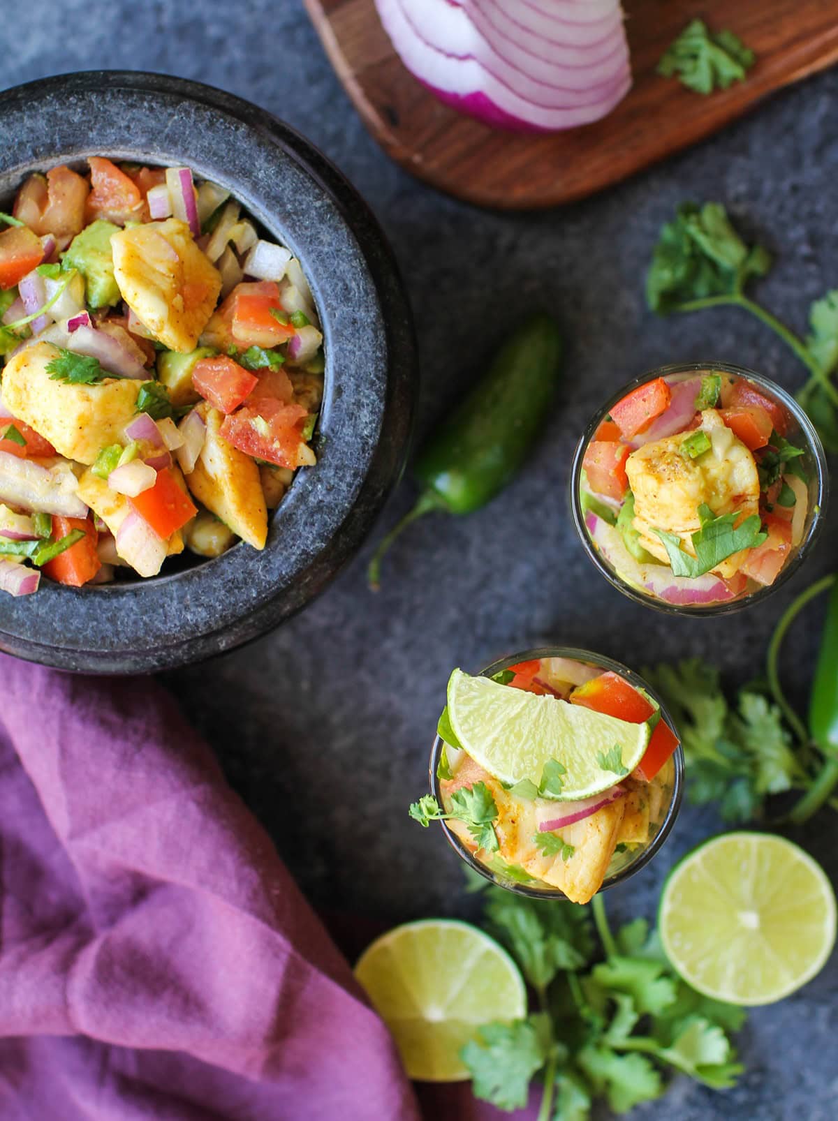 large stone bowl and two serving glasses of halibut ceviche, ready to serve