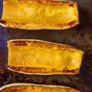 Roasted delicata squash face-up on a baking dish, ready to eat.