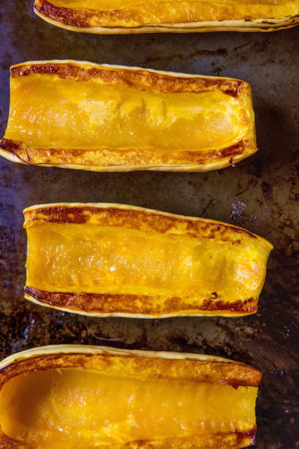 Roasted delicata squash face-up on a baking dish, ready to eat.