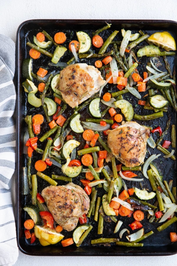Large sheet pan of veggies and chicken thighs fresh out of the oven.