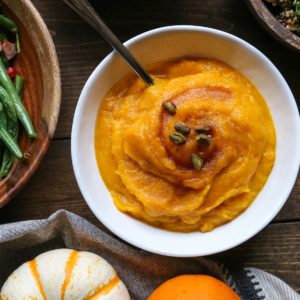 Bowl of kabocha squash mash with other side dishes all around.