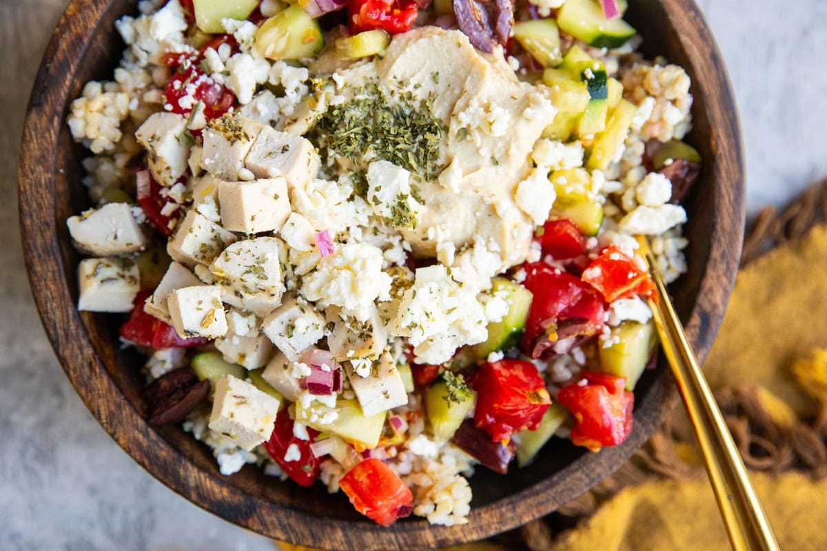 Big wooden bowl of Mediterranean chicken and hummus