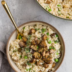 Big bowl of mushroom risotto with the pot with the rest of the recipe to the side and a napkin to the side.