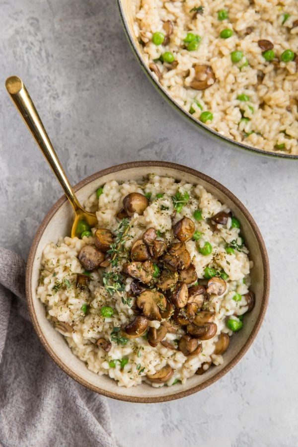 Big bowl of mushroom risotto with the pot with the rest of the recipe to the side and a napkin to the side.