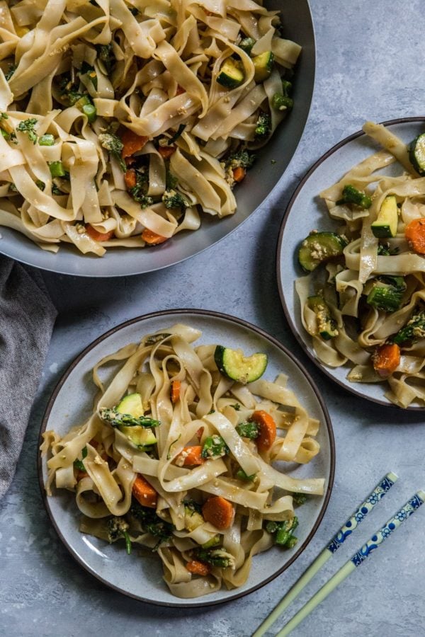 Two plates of Pad See Ew with the wok of noodles to the side.