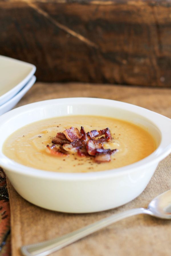 Bowl of cauliflower soup with crispy bacon on top.