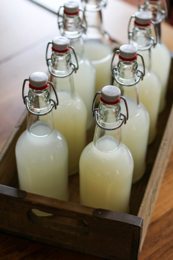 Wooden serving tray with eight bottles of ginger beer inside on a wood table