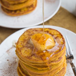 Gluten-Free Flourless Protein Pumpkin Pancakes with honey being drizzled on top, ready to serve.