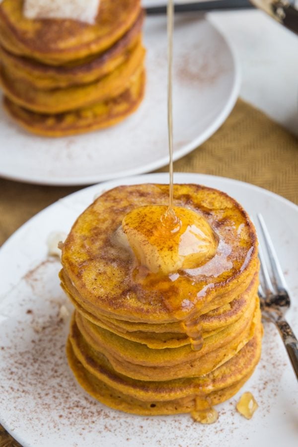 Gluten-Free Flourless Protein Pumpkin Pancakes with honey being drizzled on top, ready to serve.