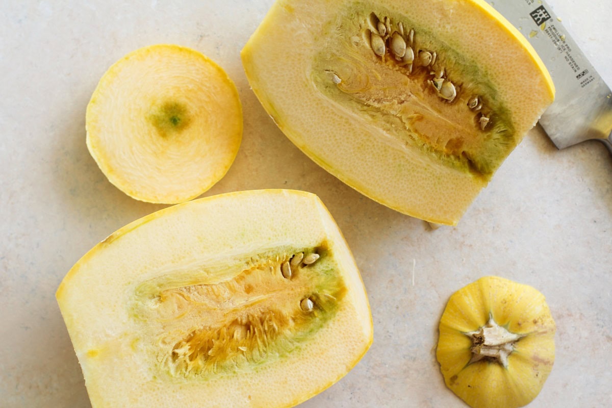 Spaghetti squash cut in half on a backdrop, cut side up to reveal the seeds and insides.