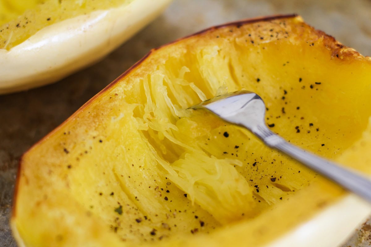 Fork pulling on the strands of spaghetti squash, ready to use in a recipe.