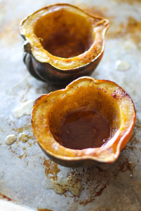 Two acorn squash halves sitting on a baking sheet.