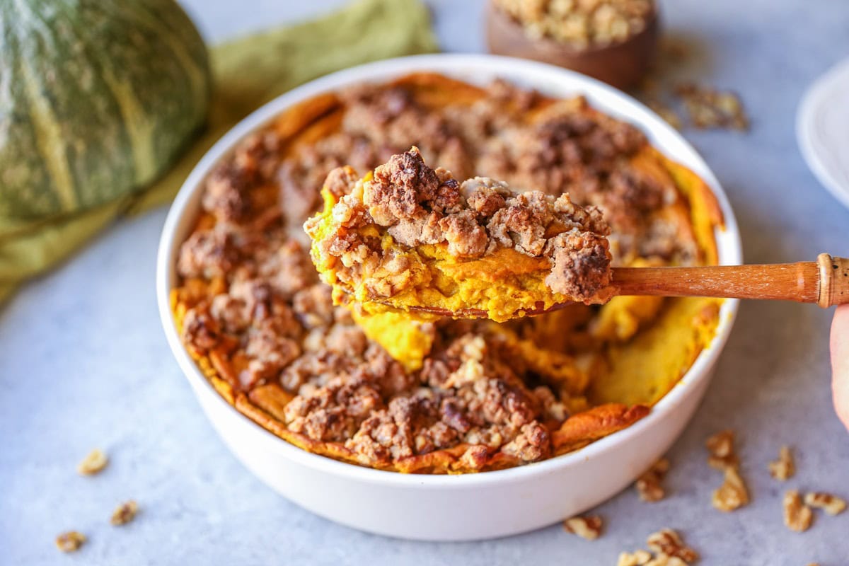 Casserole dish full of kabocha squash casserole, taking a scoop out.