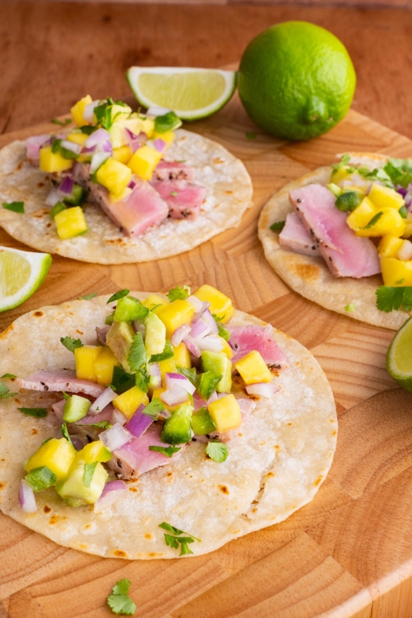 Seared Ahi Tacos with Mango Avocado Salsa on a wooden cutting board, ready to eat.
