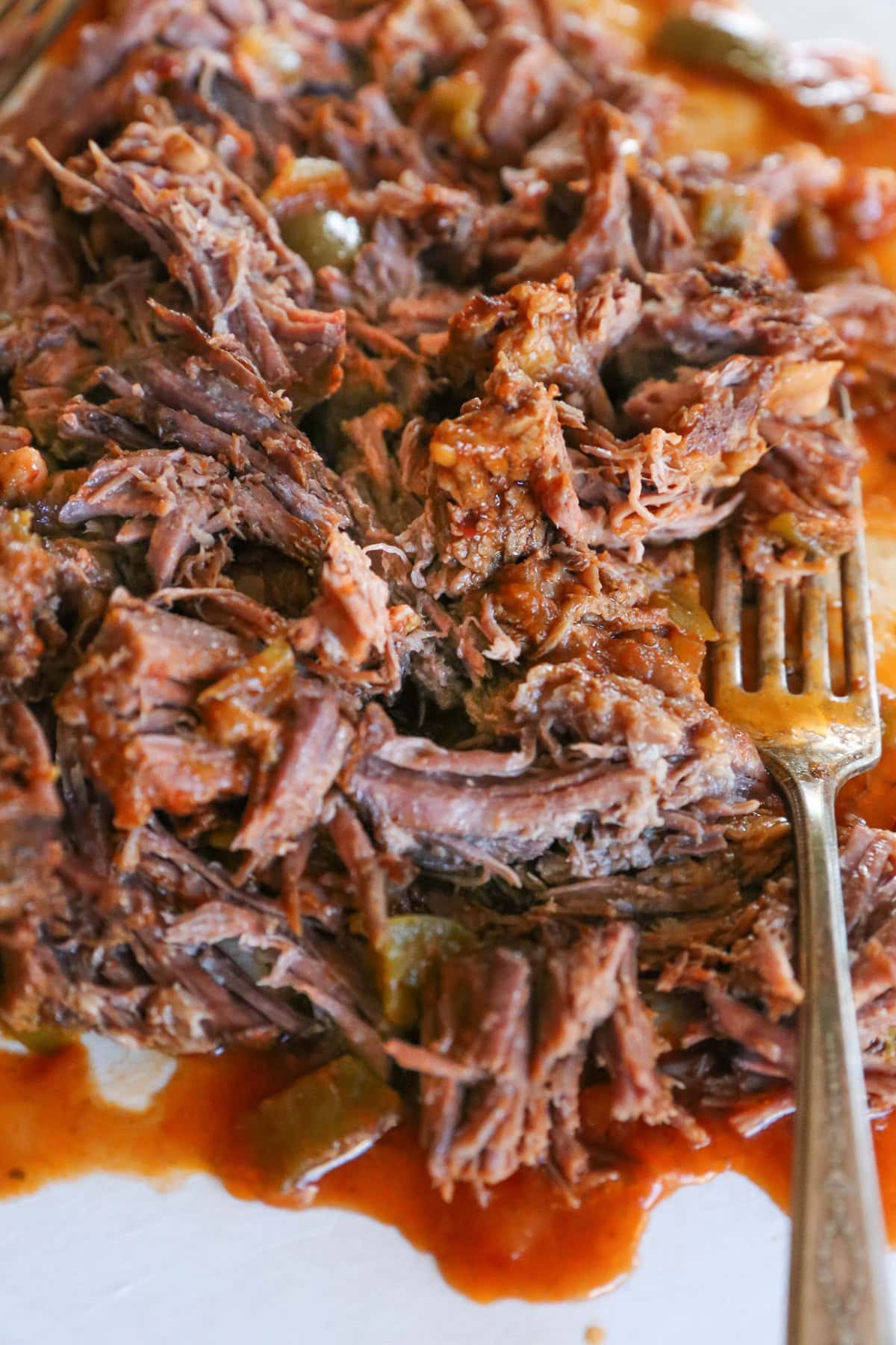 shredded cuban beef on a cutting board with a fork. Ready to serve.