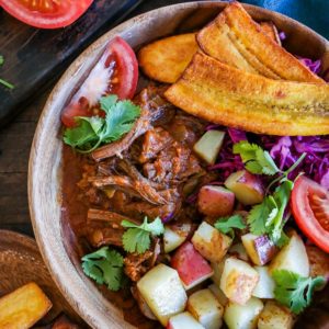 Cuban shredded beef bowl with roasted potatoes, shredded beef, plantains, and fresh tomatoes.