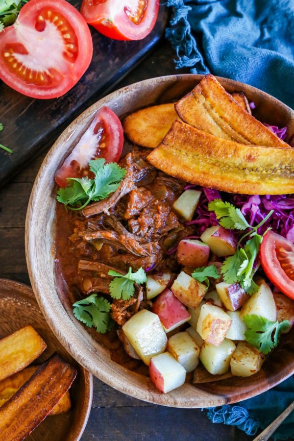 Cuban shredded beef bowl with roasted potatoes, shredded beef, plantains, and fresh tomatoes.