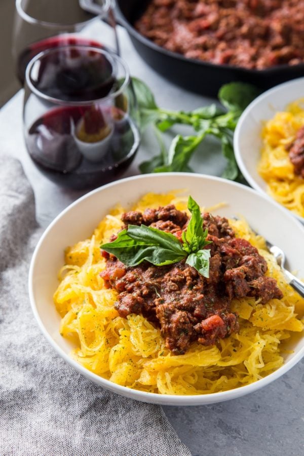 large white bowl of spaghetti squash with tomato based meat sauce on top.