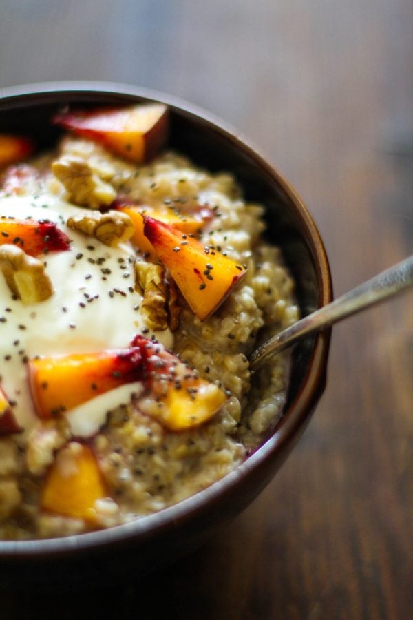 Bowl full of steel cut oatmeal with chia seeds, walnuts, and peaches on top.