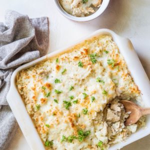 Large casserole dish full of tuna casserole fresh out of the oven with a small ramekin to the side full of a portion of casserole.