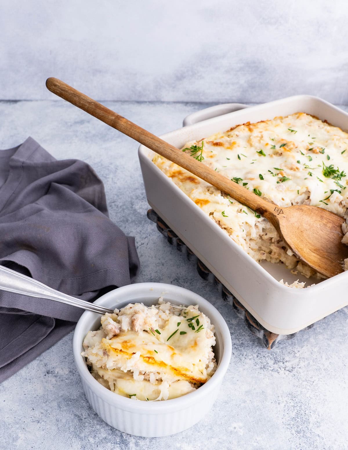 Small ramekin full of tuna rice casserole with the casserole dish in the background.