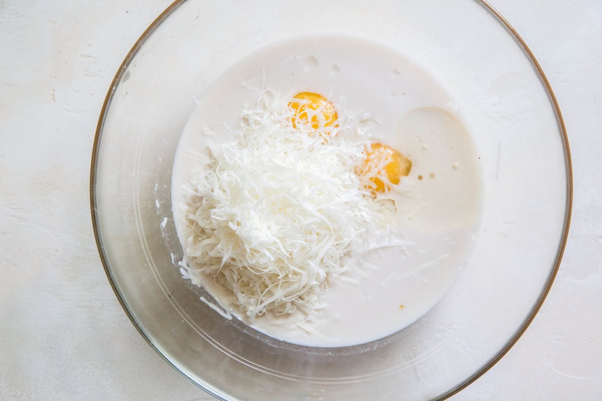 Milk, eggs, oil, and cheese in a large mixing bowl, ready to be mixed together.