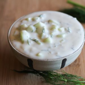 Bowl of homemade tzatziki sauce with fresh dill around. Ready to use.