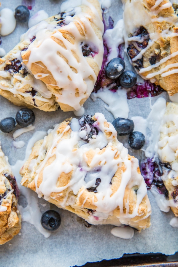 Baking sheet of gluten-free blueberry scones drizzled with glaze.