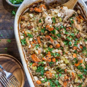 casserole dish of wild rice chicken casserole on rustic backdrop with two plates to the side